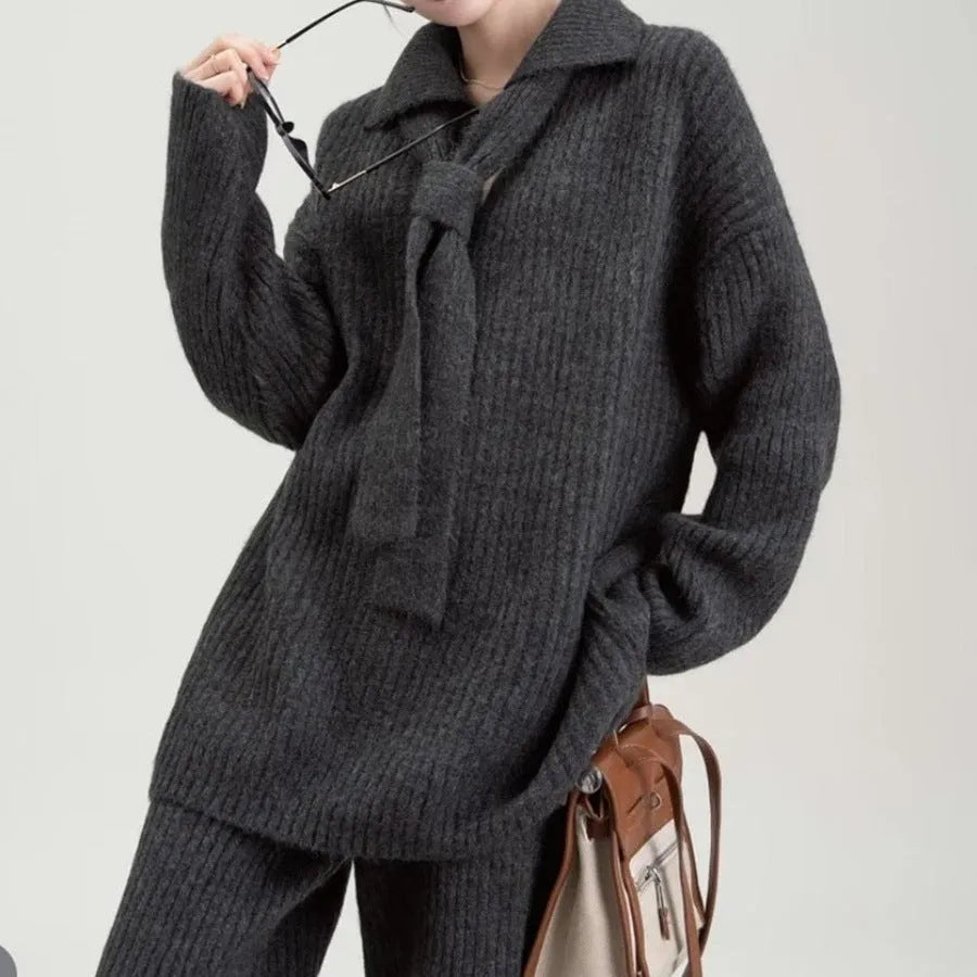 Beige women's knitted sweater suit set with collage stitch detail on top and trousers on a hanger.