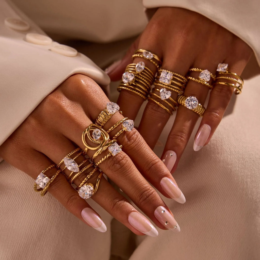 Geometric gold-coloured stainless steel ring with open mouth design on a plain background