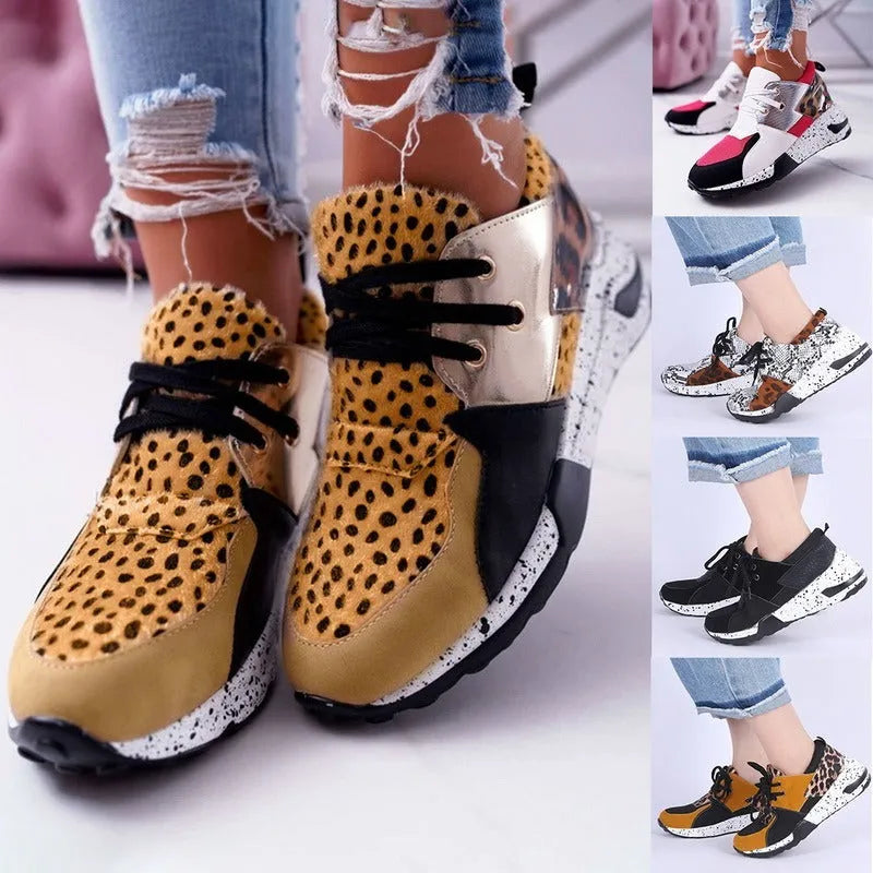 Women's black suede casual sneakers with a low wedge heel on a wooden floor.