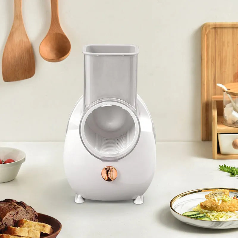 White electric vegetable slicer with rotary grater, blade barrel, and suction base on a kitchen counter.