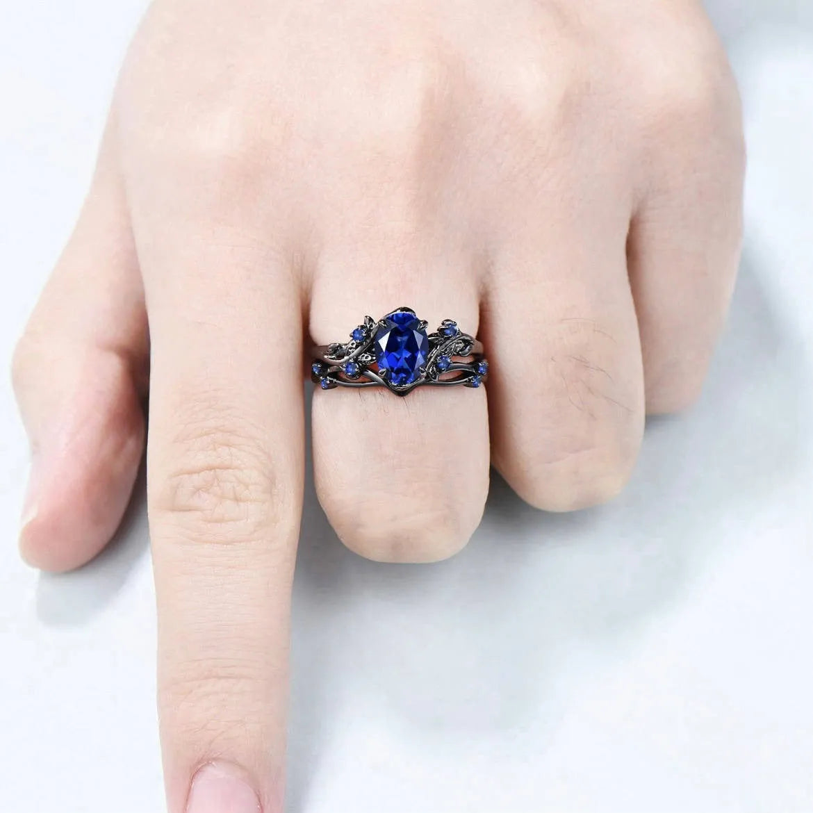 Geometric gun black couple ring for women with a single inlaid navy blue rhinestone.