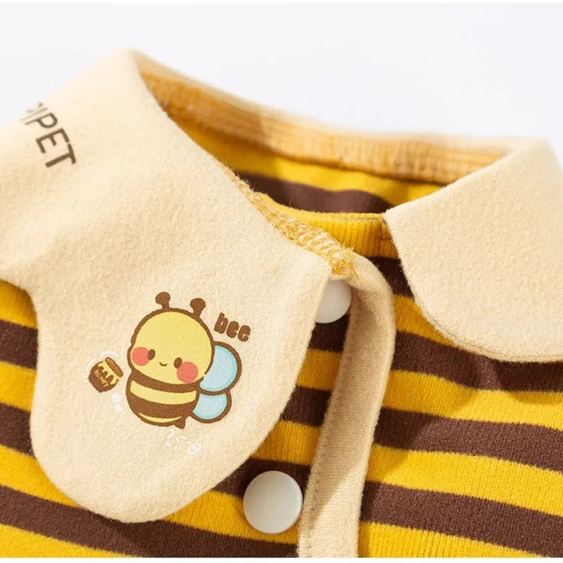 Yellow dog pajamas with bee pattern and lapel on small dog standing indoors