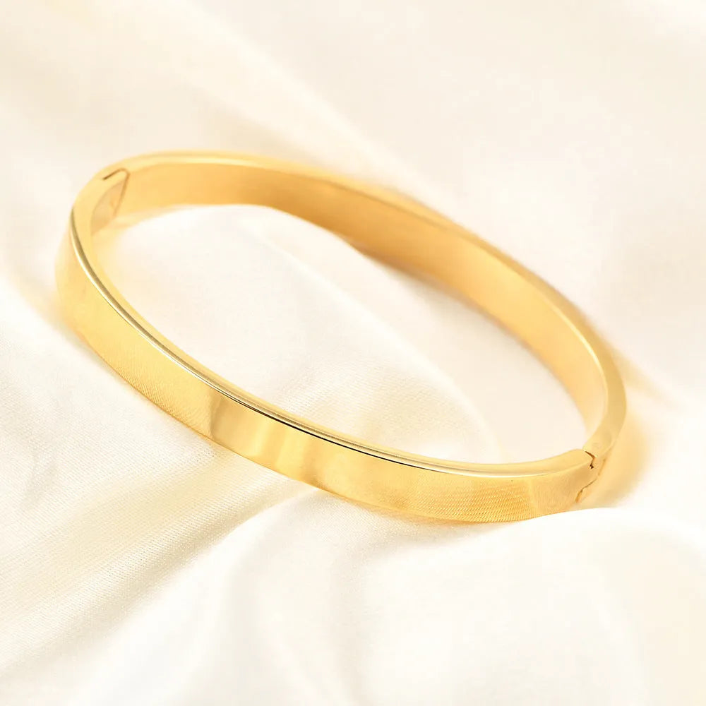 Stainless steel snap bracelet with polished finish in gold colour on a white background