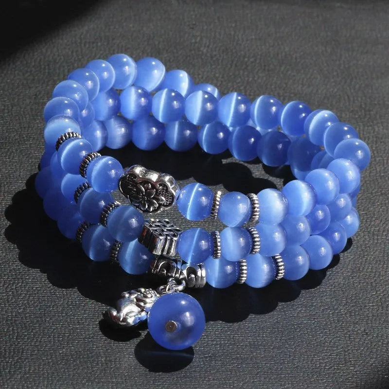 Women's opal bracelet with three interlocking rings, a Lucky Cat charm, and geometric stones in various colours.