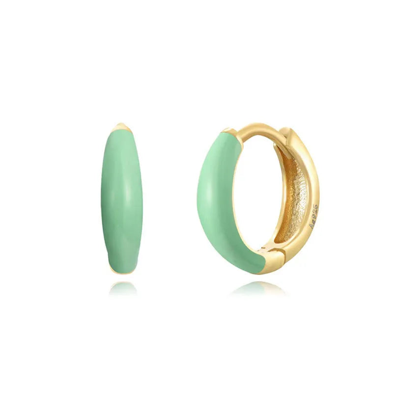 A pair of glossy light green epoxy oval earrings with a U-shaped curve and silver-coloured post on a grey background.