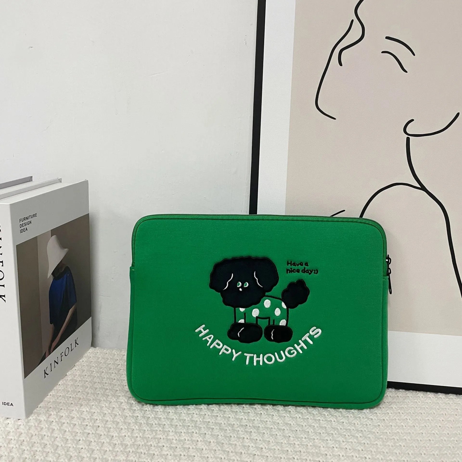 Embroidered animal design laptop sleeve in polyester, shown next to a laptop.