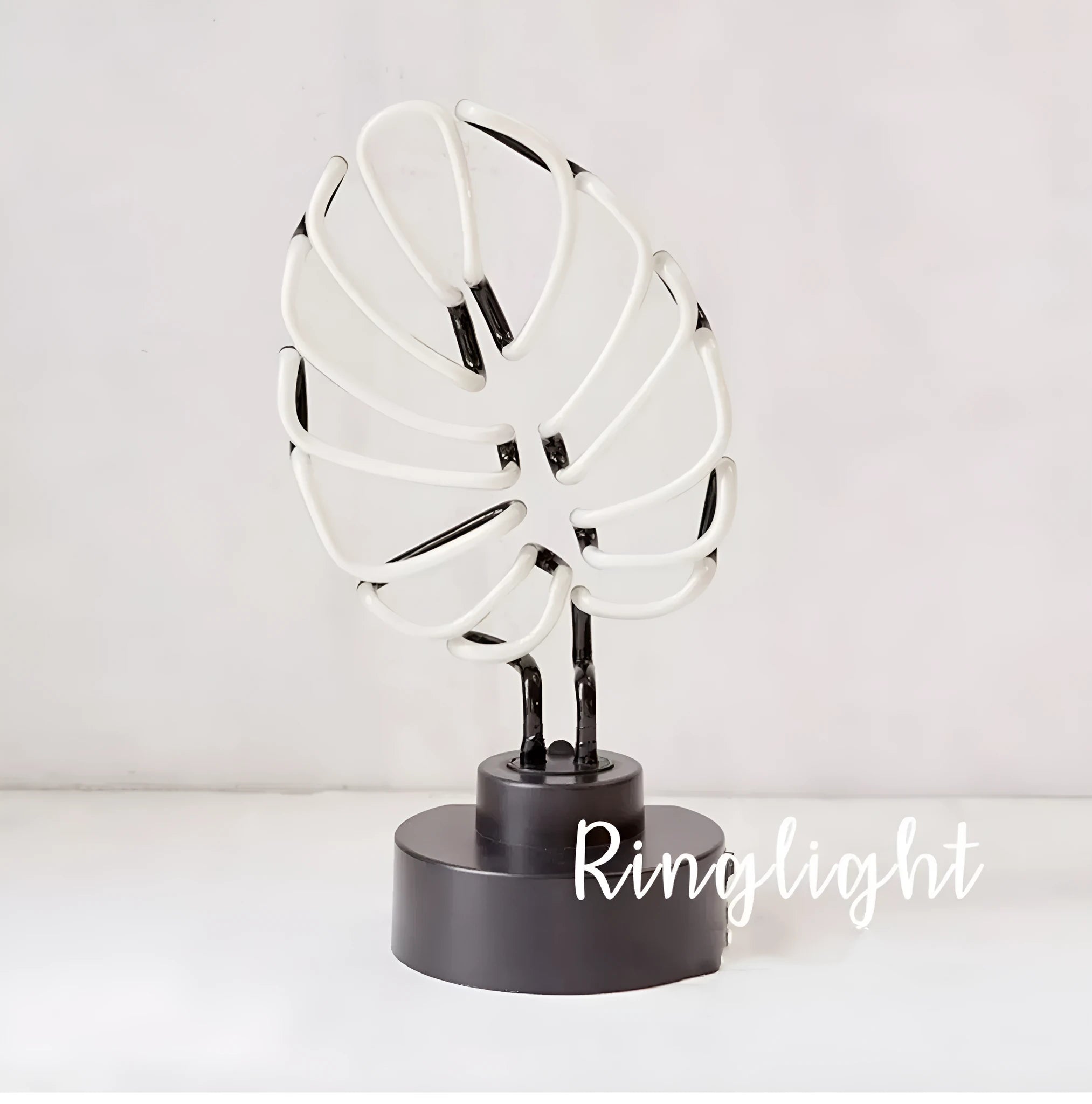 Minimalist white bamboo-shaped desk lamp emitting a soft green glow from its tube.