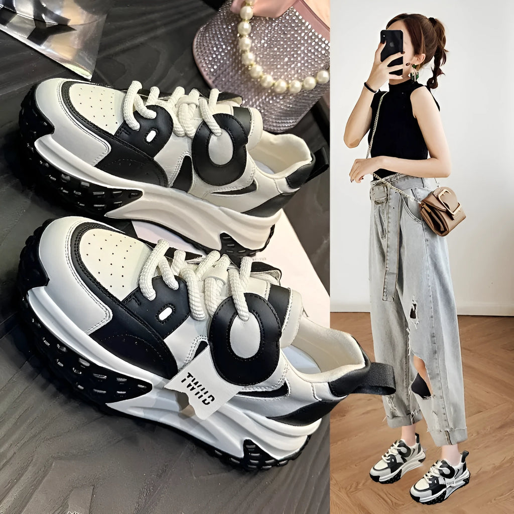 A pair of thick-soled leather casual sports shoes in a black and white colourway with a lace-up front.