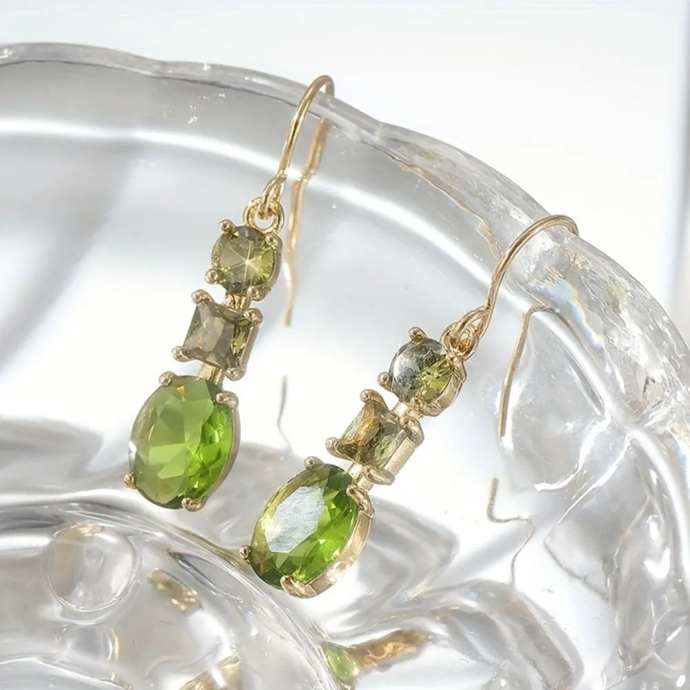 Green geometric copper earrings with a quadrilateral shape on a plain background.