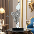 Tall modern sculptured character ornament in a metallic rose gold finish on a table.