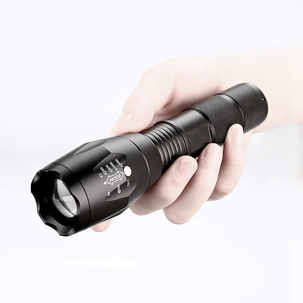 Black aluminium alloy zoomable focus LED torch with antiskid grip on a textured surface.