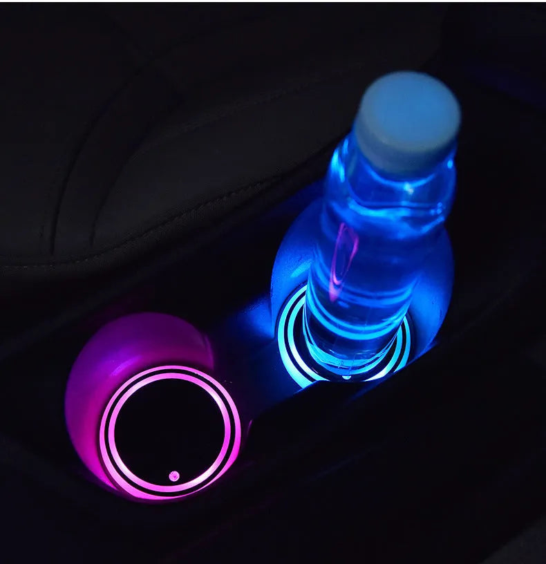 Colourful LED light-up car cup holder coaster with USB cable on a car centre console.