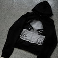 Black women's loose-fit hoodie with a cartoon print, shown in a casual setting.