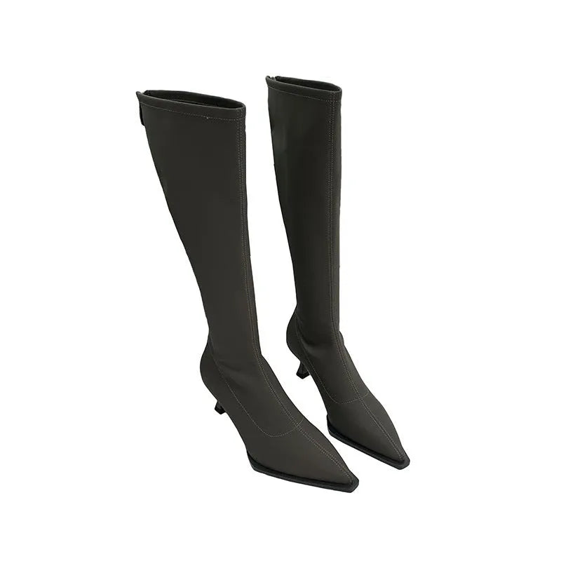 Black pointed toe below-the-knee women's boots with a stiletto heel and a visible back zipper on a plain background.