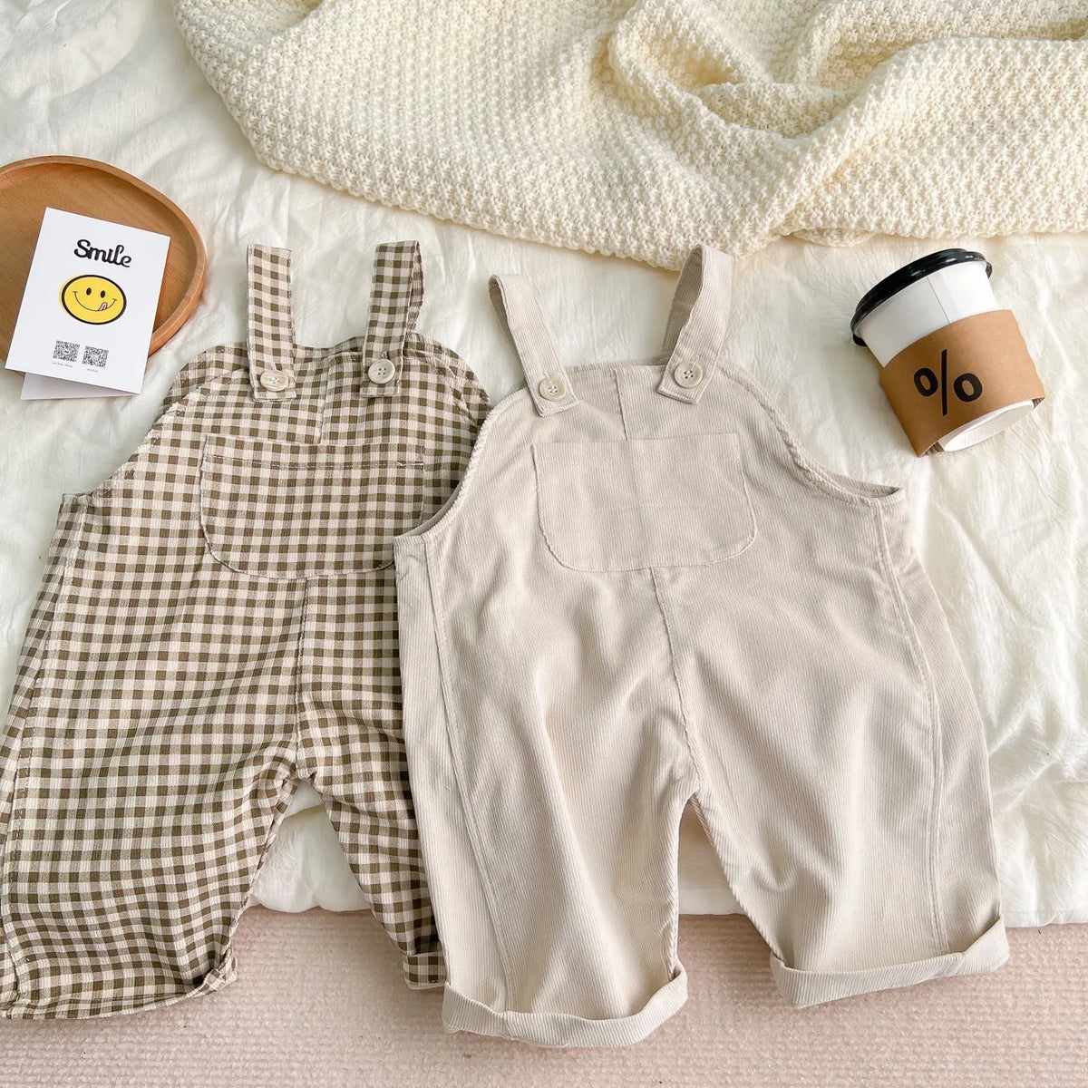 Unisex corduroy suspender overalls in creamy-white or brown plaid, with large pockets and double-breasted closure, for spring and autumn.