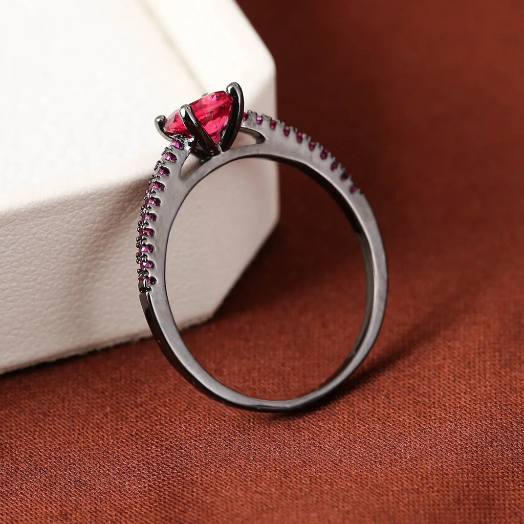 Close-up of a hexagonal geometric copper ring with a central zircon stone in a gun black and purple electroplated finish.