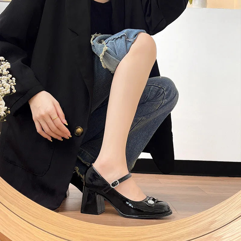 Women's black patent leather chunky heel shoes with a round toe and buckle fastening.