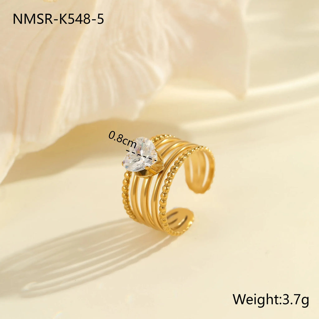 Geometric gold-coloured stainless steel ring with open mouth design on a plain background