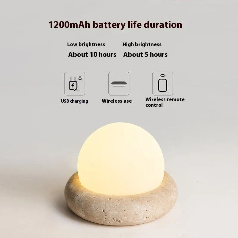 Circular modern night light with remote control on a wooden bedside table.