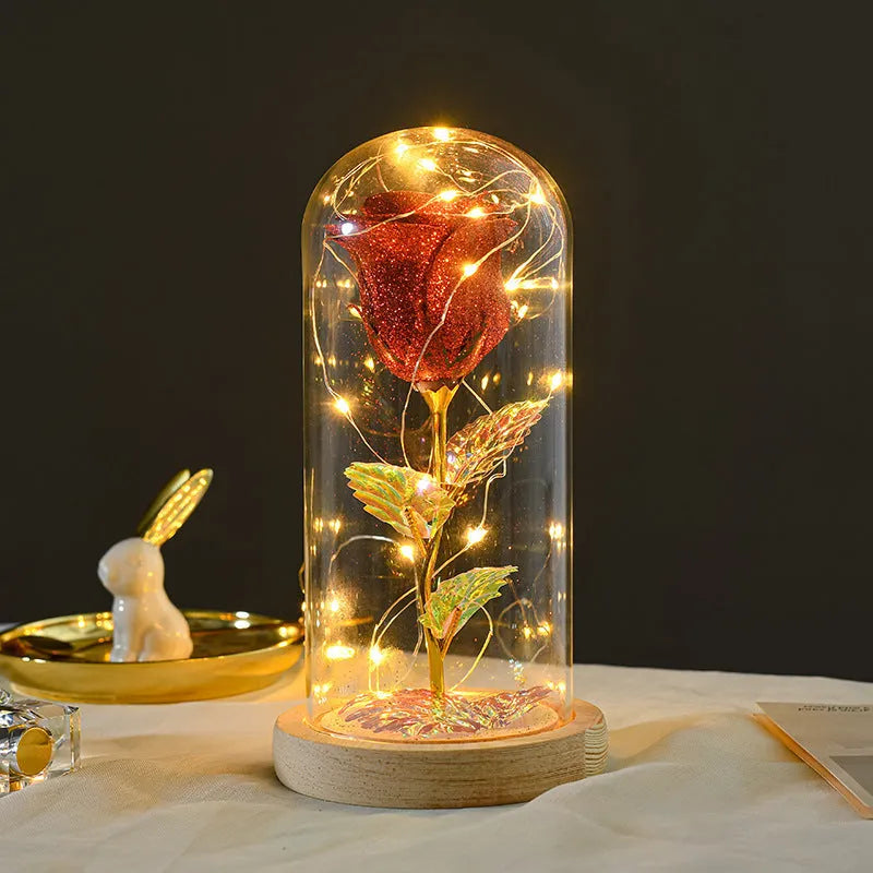 Red eternal rose in glass cover with warm white LED strip lit on dark surface