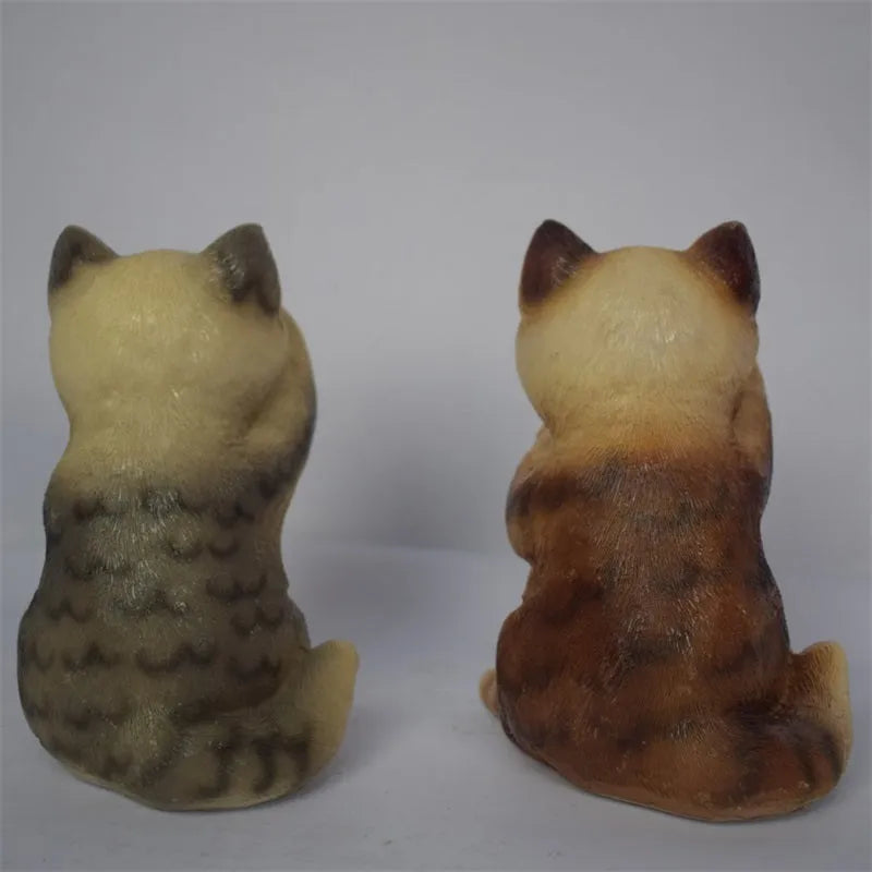 Brown resin cat-shaped solar garden light illuminating in a evening garden setting.