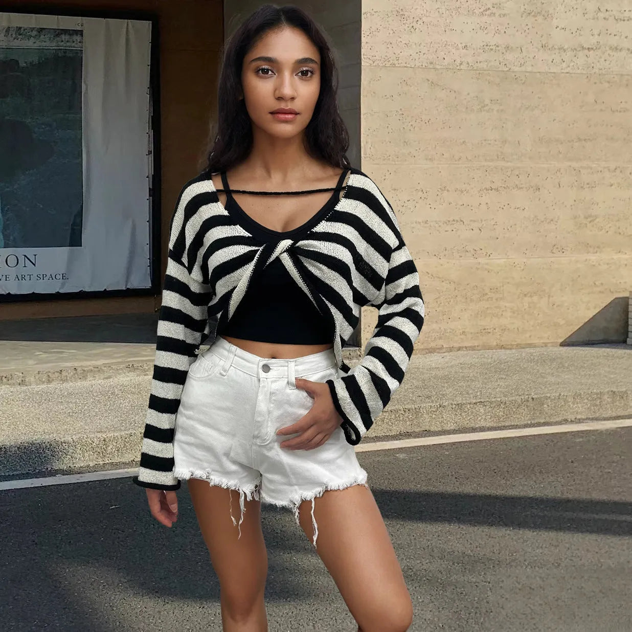 Woman wearing a striped long-sleeve sweater in mercerised cotton, showing front and back wearability with exposed navel detail.