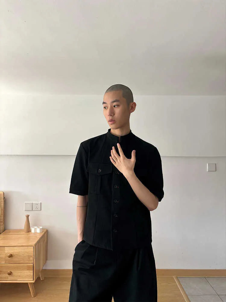 Handmade black half-sleeve hunting shirt with a shirt collar on a hanger.