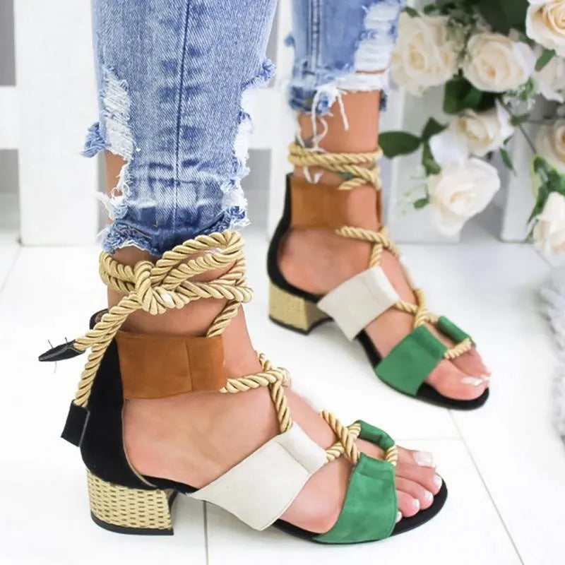 Women's beige suede sandals with thick heel and ankle strap on a foot.
