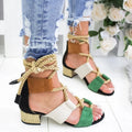 Women's beige suede sandals with thick heel and ankle strap on a foot.