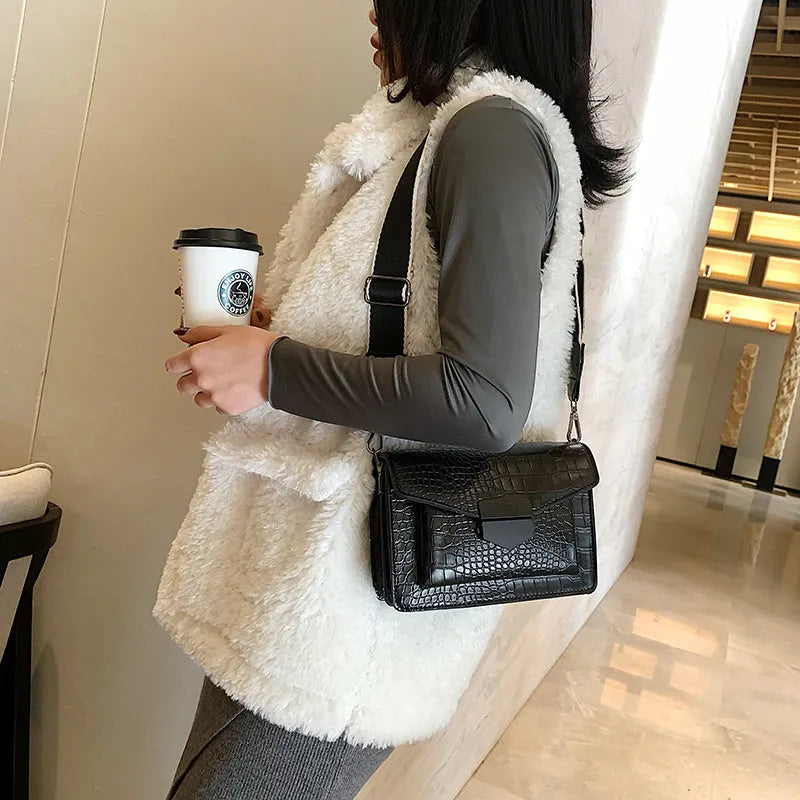 Vintage style black crossbody bag with an adjustable shoulder strap on a mannequin.