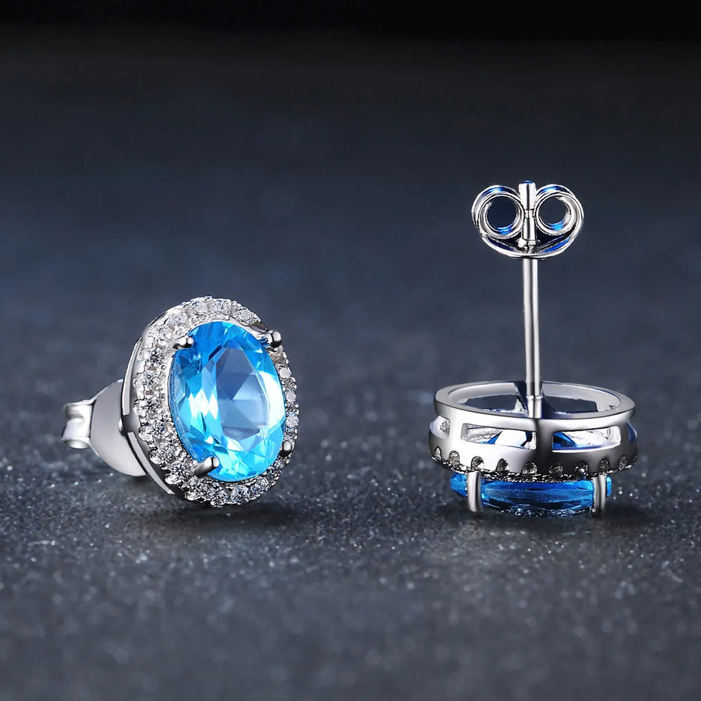 Geometric women's jewellery set in sterling silver with blue topaz gems, showing necklace, earrings, ring, and pendant.