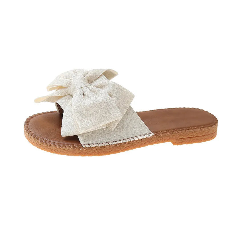 Women's beige suede slip-on sandals with a bow detail and soft rubber sole