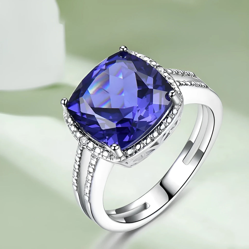 A sterling silver ring for women with a bright blue tanzanite stone, shown on a hand.
