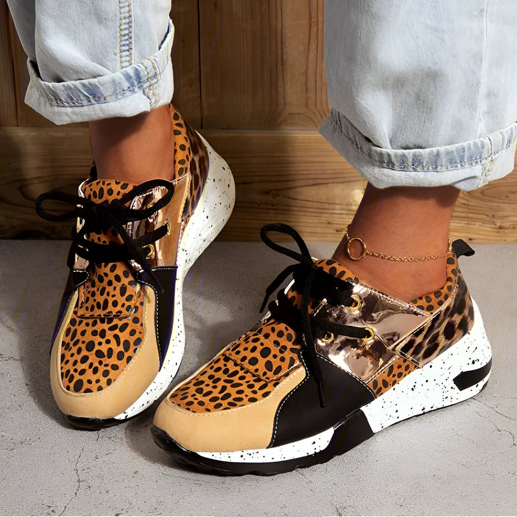 Women's black suede casual sneakers with a low wedge heel on a wooden floor.