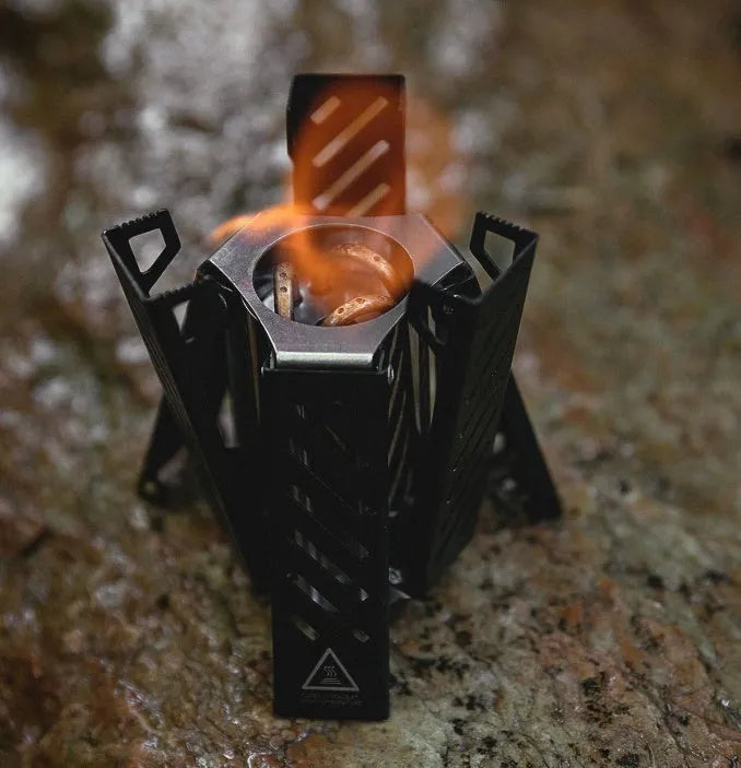 Hexagon alcohol camping stove folded showing black/silver alloy construction with dimensions 9.5x8.5x15cm