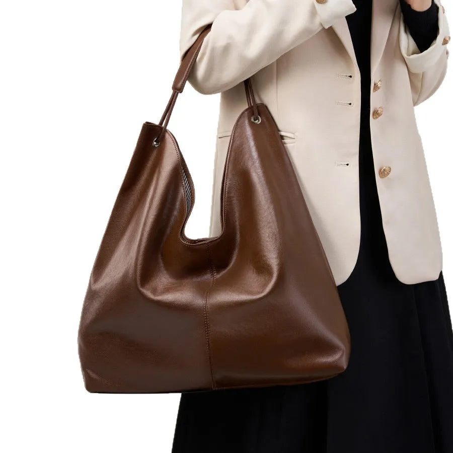 Brown genuine leather tote bag with contrast stitching and large capacity, front view on white background