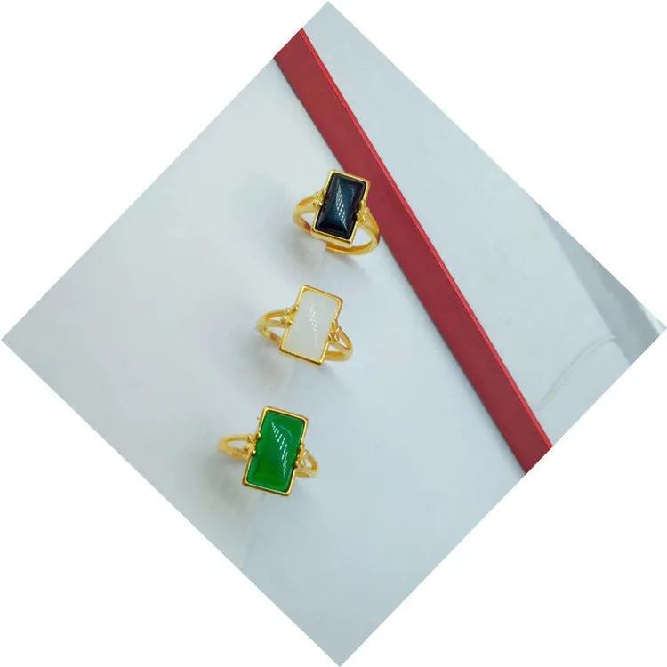 Adjustable brass gold-plated ring with a green artificial gemstone inlay on a finger.