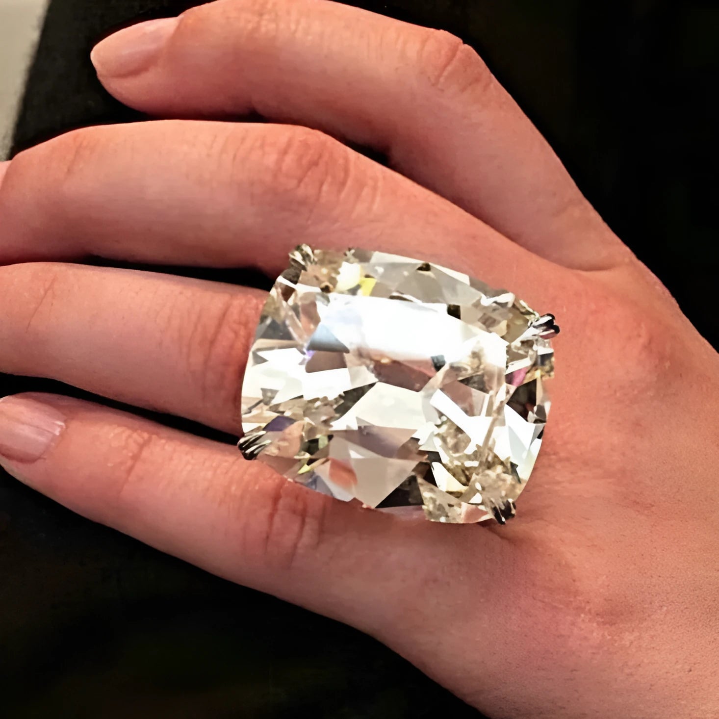 Women's simple square diamond ring in white gold colour on a hand, showing geometric band.