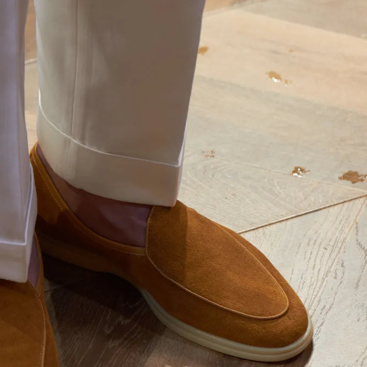 Men's brown genuine leather handmade loafers on a white background, showing the low-cut slip-on design and textured sole.