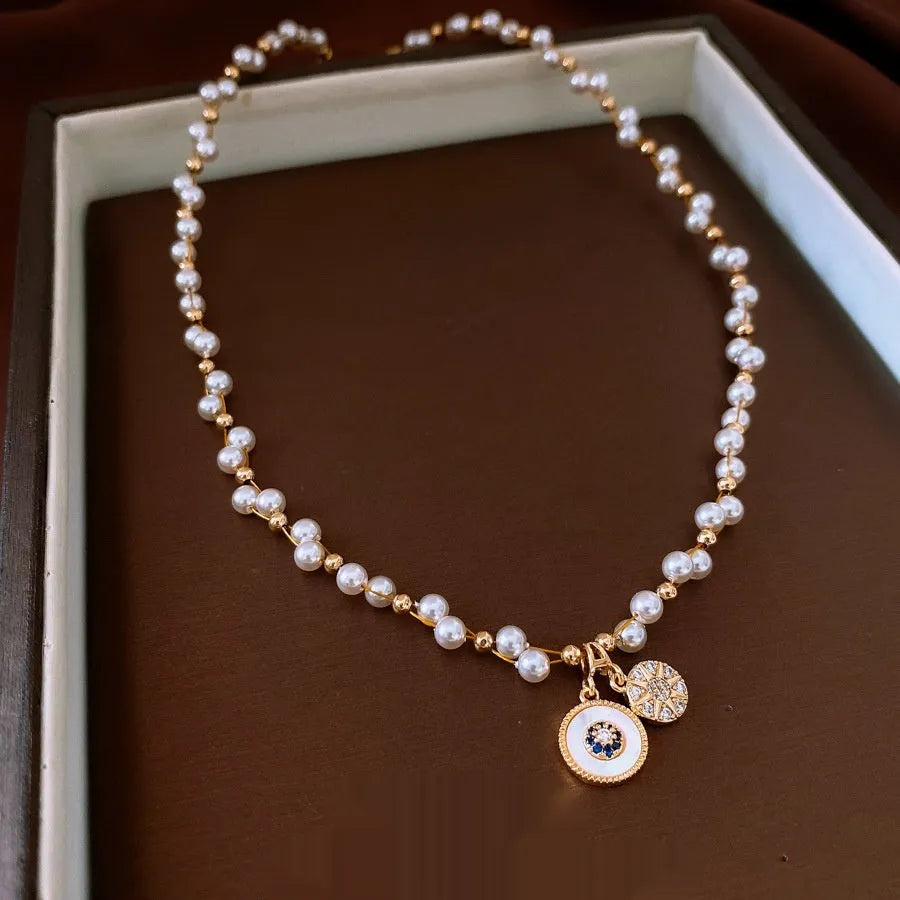 Gold electroplated adjustable clavicle necklace with round zircon and imitation pearl pendant.