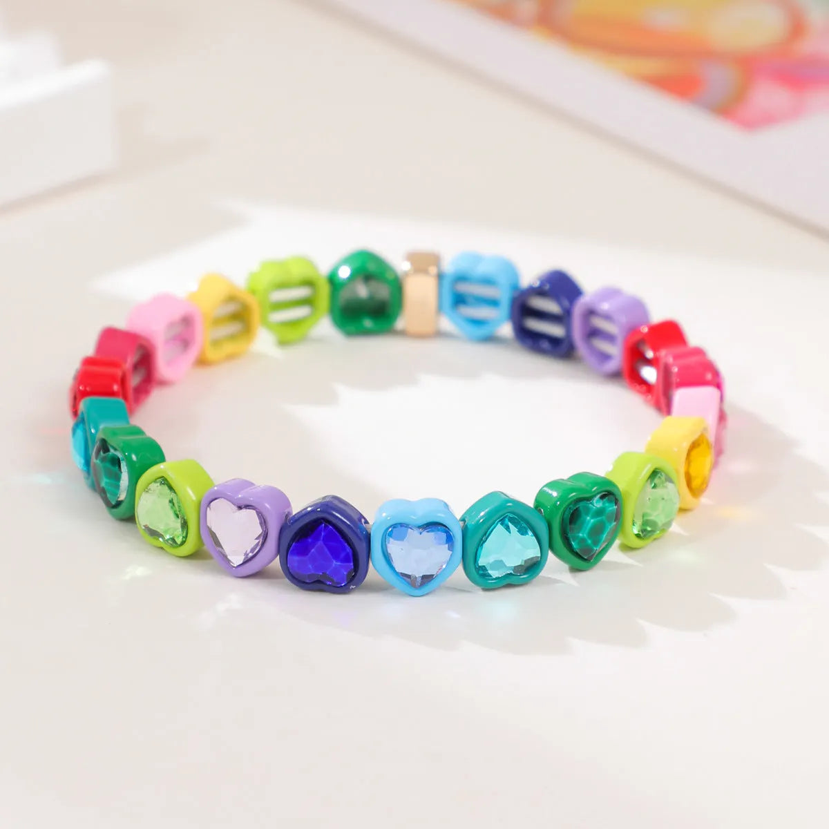 Rainbow enamel heart charm bracelet on alloy base with diamond treatment, stretch band, multicolour design.
