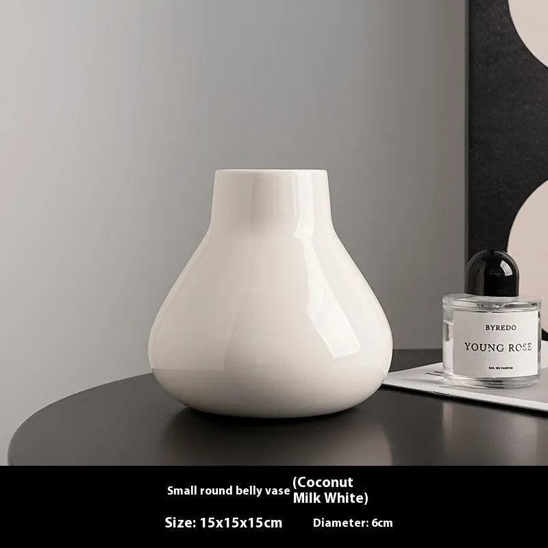 Modern round belly ceramic vase with coloured glaze, shown in black and white, some with artificial flowers.