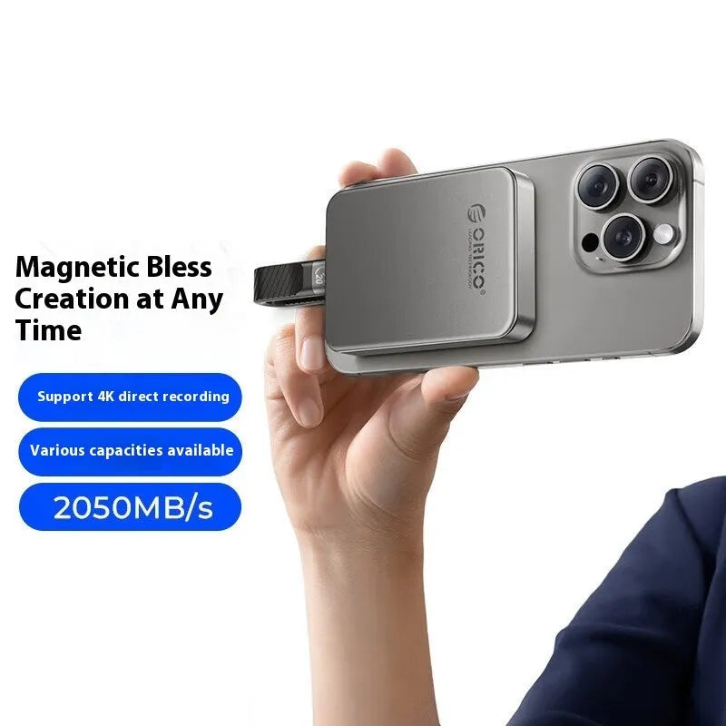 Grey ultra-thin magnetic mobile solid state drive with C to C cable and magnetic suction ring on a table.