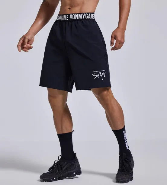 Men's loose black cropped sports shorts with an elastic waistband on a grey background
