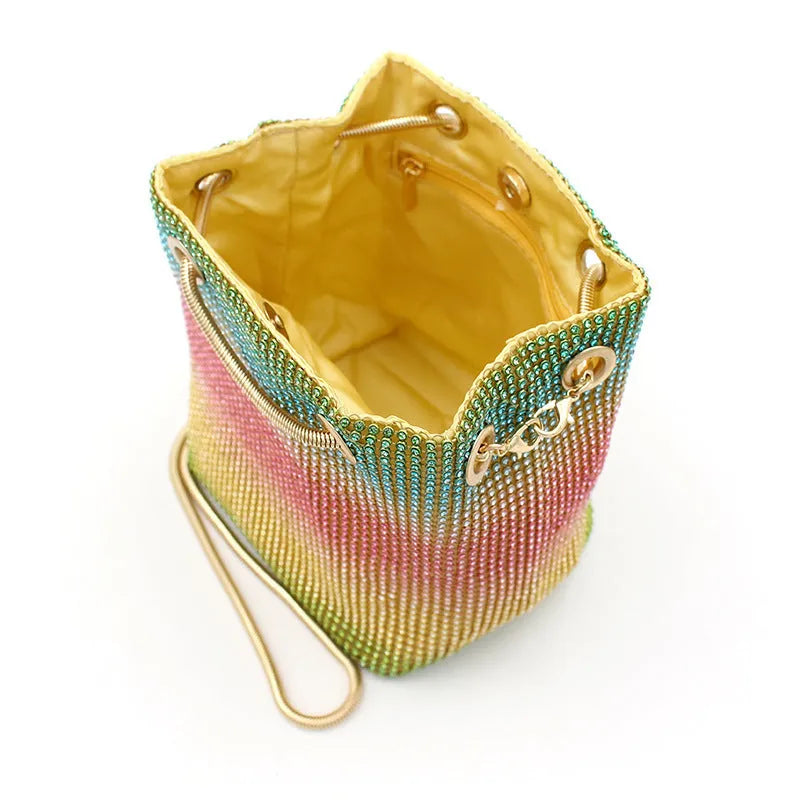 Soft rainbow rhinestone bucket bag with adjustable metal chain strap on a 28cm circular base.