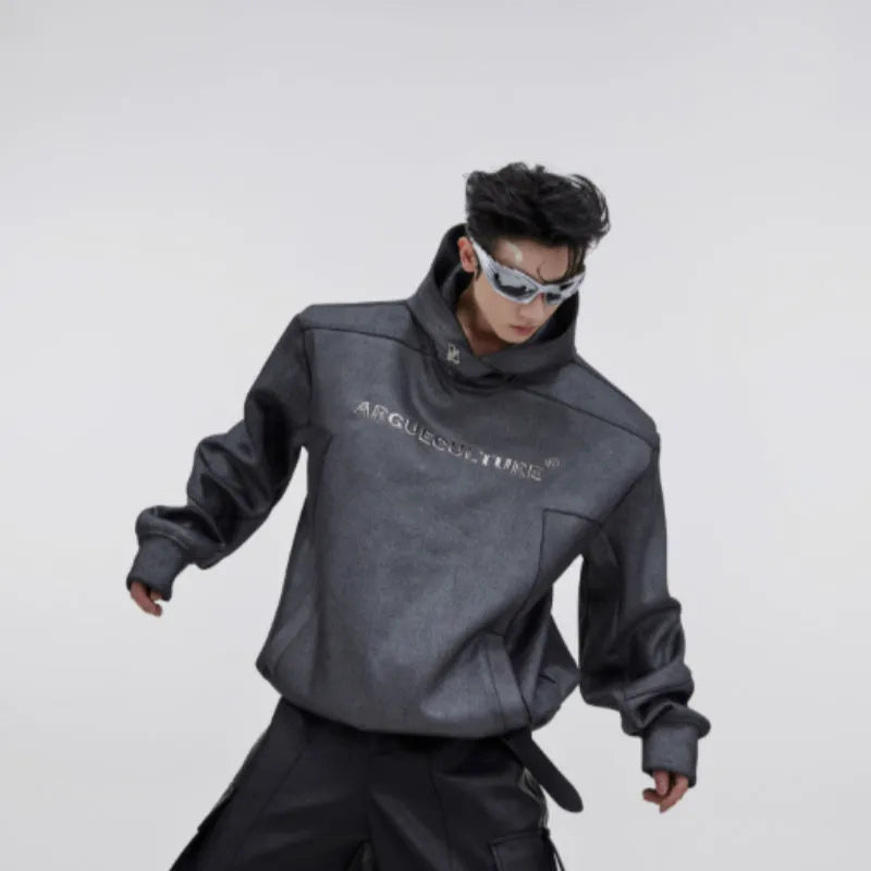 Man wearing a loose black hooded sweater with metallic 3D printed design and structured shoulder pads.