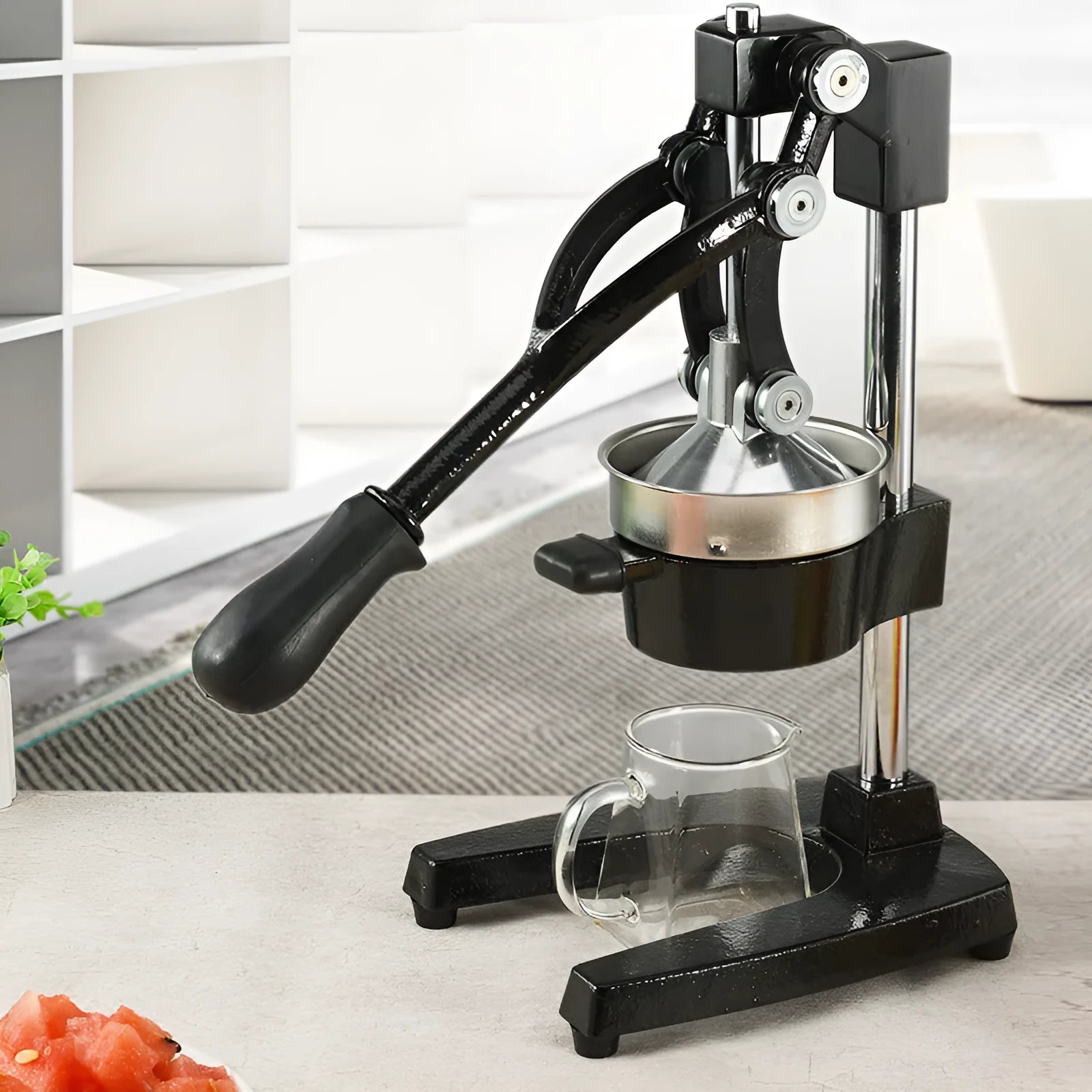 Black ductile cast iron manual citrus juicer with stainless steel strainer on a kitchen counter