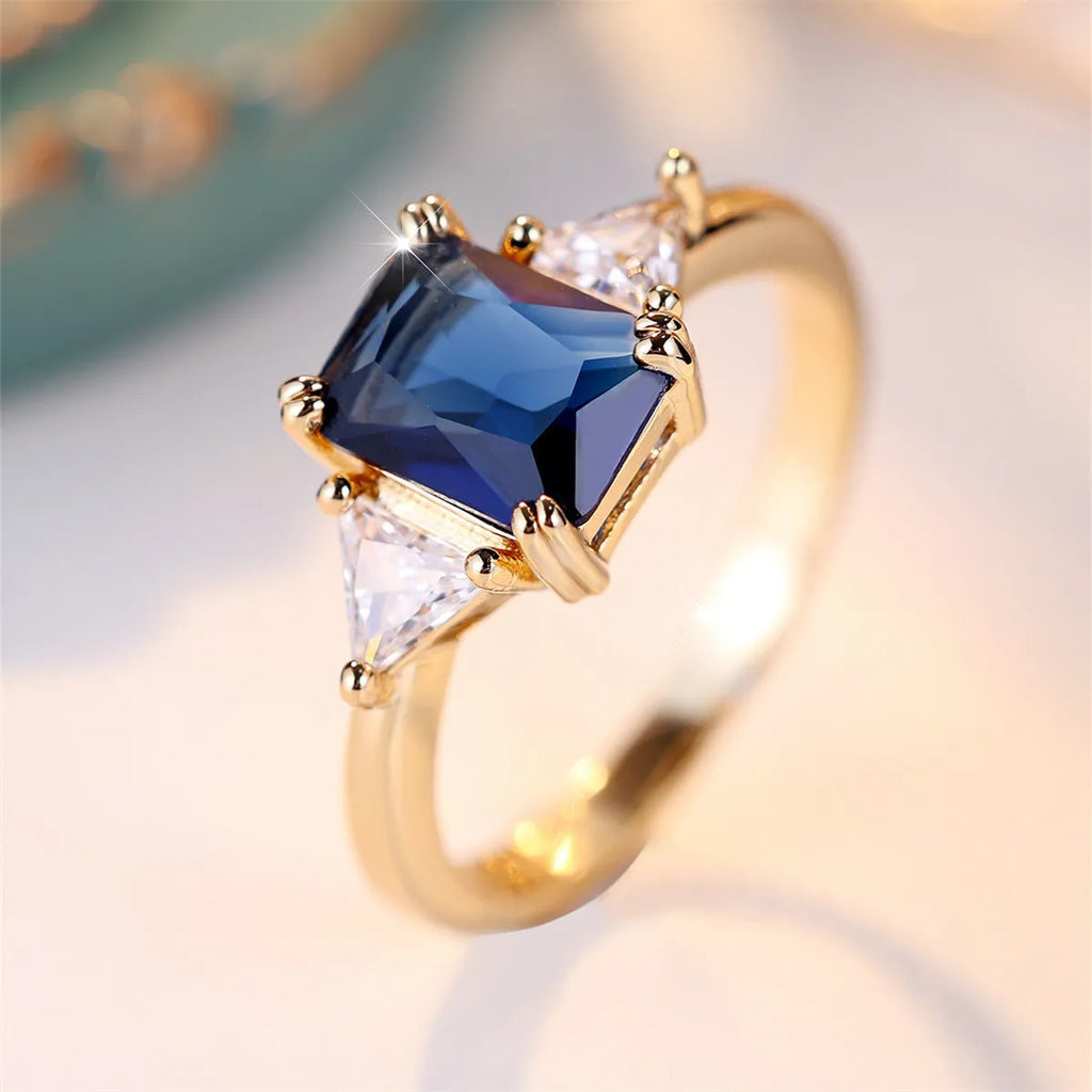 A gold sapphire blue rectangular copper ring for women on a jewellery display.