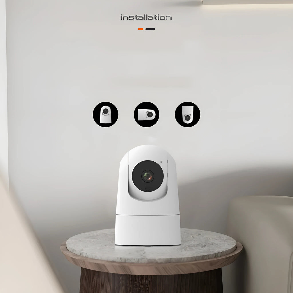 White indoor security camera with wide-angle lens on a table, showing power cable and mounting bracket.