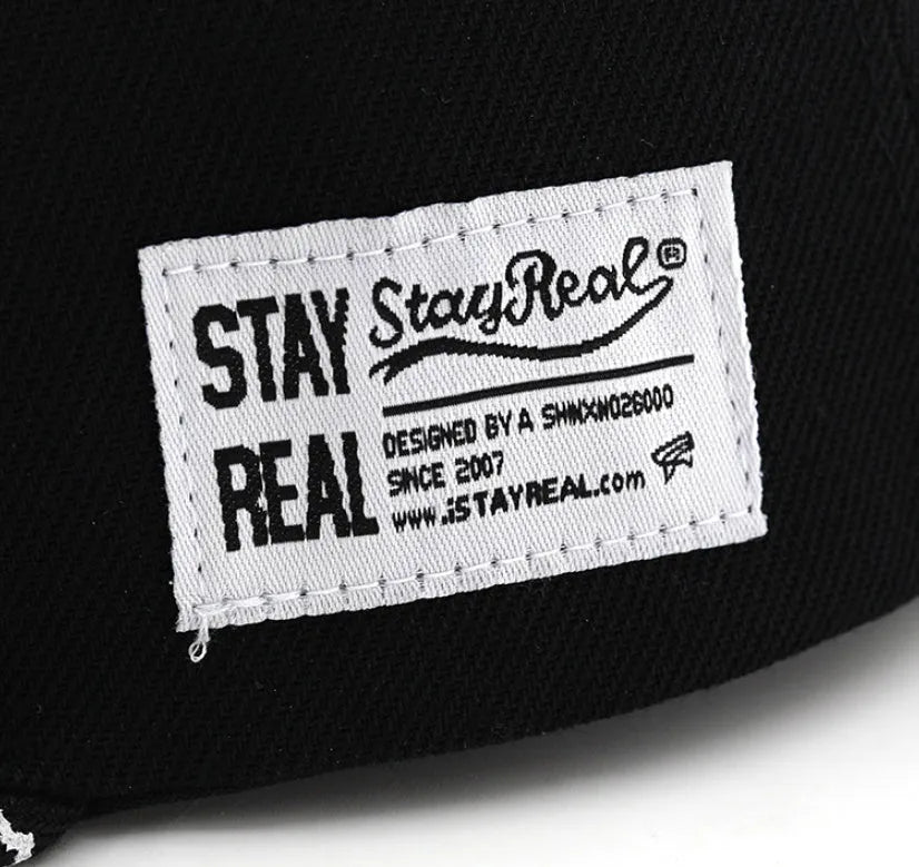 White and black adjustable cotton baseball cap with embroidered letters on the front, showing dome crown and adjustable strap.